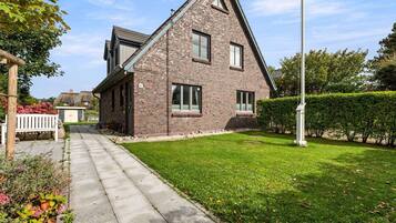 A modern two-story house with a brick exterior, a visible garage, and a well-maintained lawn.