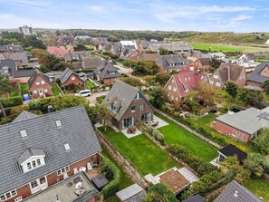 Zona residencial con casas, un campo cubierto de césped y un edificio a lo lejos.
