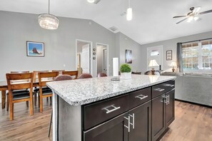 A modern kitchen with a granite countertop, dark cabinetry, and a ceiling fan. - Perfect Getaway Home, Close to Rainbow Springs! (Citrus Springs)