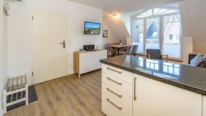 A modern kitchen with a large island, wooden flooring, and a dining area with a table and chairs. - Austernfischer App. 4 - 3-room apartment for up to 4 people with balcony. (Sylt)