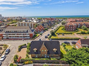 A residential area with a mix of modern and traditional architecture, including a prominent building with a large balcony and a smaller house with a dark roof.