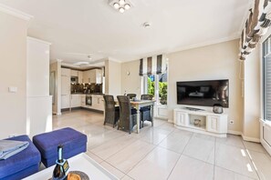 A modern living room with a TV, sofa, and dining area.