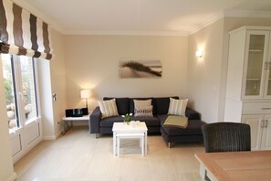 Uma sala de estar com sofá, mesa de centro, abajur e um quadro na parede.