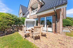 A house with a brick exterior, a stone wall, and a patio with wooden furniture.