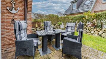 Eine Terrasse im Freien mit Backsteinmauer, Tisch und vier Stühlen.