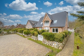 Ein zweistöckiges Haus mit Stein Fundament, befestigter Auffahrt und einem gepflegten Garten.