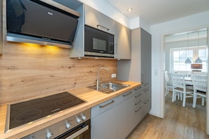 Une cuisine moderne avec un revêtement mural en bois, des appareils en acier inoxydable et un four encastré.