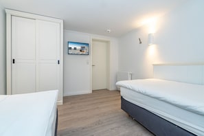 Une chambre à coucher comprenant un lit, une armoire, un téléviseur fixé au mur et un radiateur.