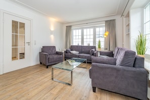 Un salon moderne avec une table basse en verre, deux canapés gris et un fauteuil gris.