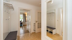 A hallway with a bench, a coat rack, and a mirrored closet door. - Nordersuite - Just behind the dunes. 4-room vacation apartment in the north of (Sylt)