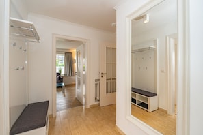 Un couloir avec un banc, un porte-manteau et une porte de placard avec un miroir.