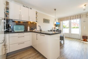 A modern kitchen with white cabinets, a granite countertop, and a built-in island.
