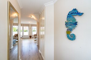 A hallway with a seahorse artwork on the wall, leading to a room with a window and a chair. - Auszeit Sylt App. 2 - Hier ist der Name Programm, Nehmen Sie Sich Eine Auszeit auf Sylt (Sylt)