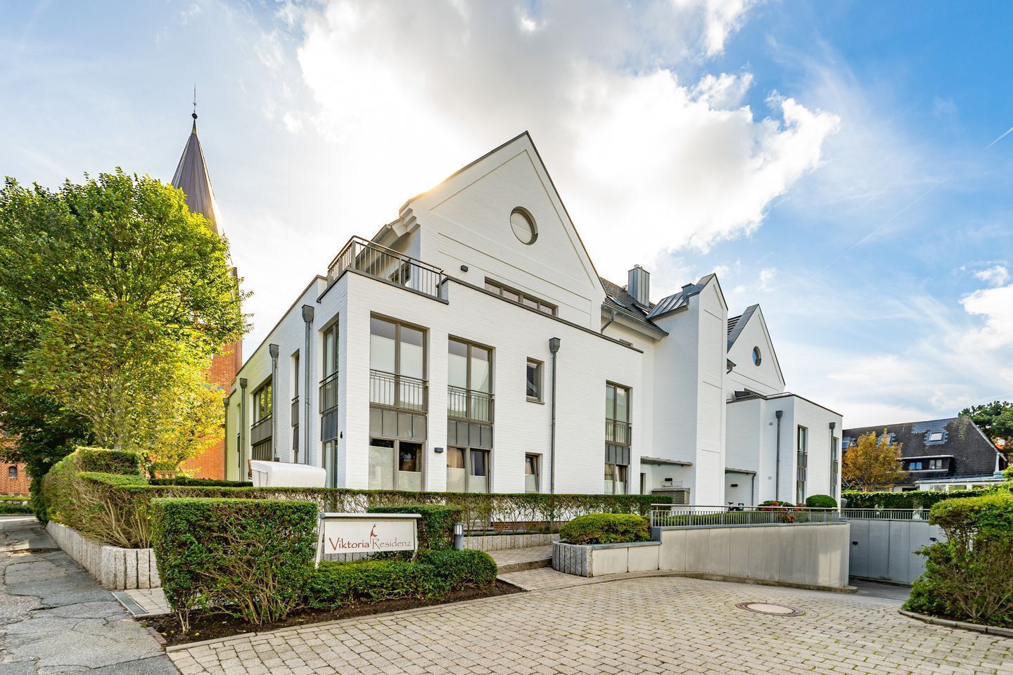 Ein modernes, weißes Gebäude mit großen Fenstern und einem Schild mit der Aufschrift "Viktoria Residenz".