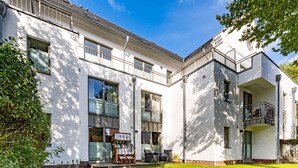 A modern white building with large windows, a balcony, and a well-maintained lawn. - Stadtresidenz App. 4 - Ebenerdige, Moderne Stadtwohnung- Kurze Wege zum Strand, mit Eigener (Sylt)