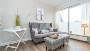 A modern living room with a grey sofa, a small white table, and a potted plant.