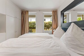Een slaapkamer met een bed, gordijnen en uitzicht.