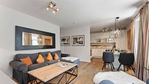 A modern living room with a sofa, coffee table, and dining area. - Beach Suite, App. 2 - Nah am Meer- Sand im Haar und Salz in der Luft (Sylt)