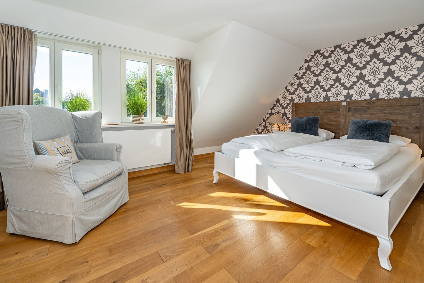 A bedroom with a bed, a chair, and a window with curtains.