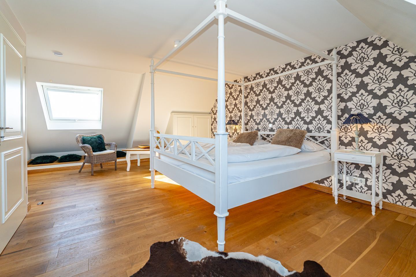 Ein Schlafzimmer mit einem Himmelbett, einem Fenster, einer Wand mit Muster und einem Holzboden.
