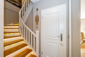 A staircase with wooden steps and white railings, a white door with a keyhole, and a decorative fish sculpture on the wall. - Winterhuus - Fantastic vacation home with garden and sauna in the south of (Sylt)