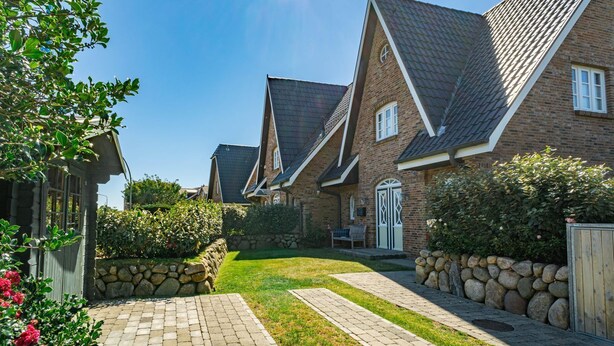 Une rangée de maisons en briques, avec des toits à deux versants et des murs en pierre.
