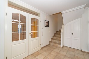 A hallway with a double door, a staircase, and a framed picture on the wall.
