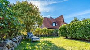 A house with a sloped roof, a stone wall, and a well-maintained lawn. - Constantin - 3-room vacation apartment for up to 4 people with garden and (Sylt)