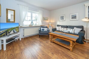 Un salon confortable avec un téléviseur, un canapé et une table basse en bois.