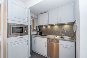 A modern kitchen with white cabinets, stainless steel appliances, and a built-in dishwasher.