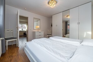 Un dormitorio con cama, armario, escritorio y silla.