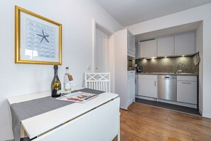 A modern kitchen with stainless steel appliances, a white countertop, and a framed picture on the wall. - Strandberg III - 2-room apartment in Westerland - only 400 meters to the beach (Sylt)