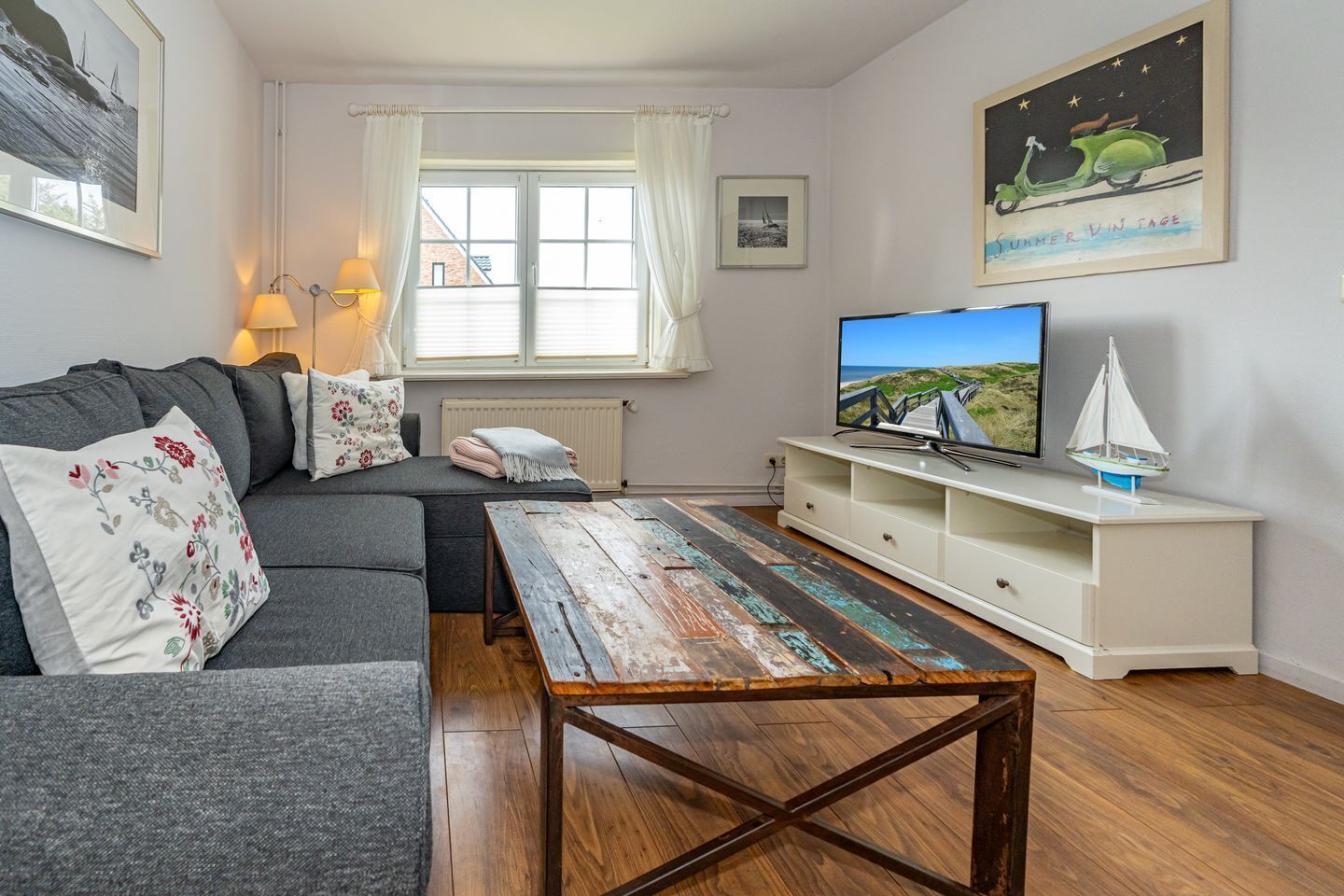 En stue med sofa, sofabord, fjernsyn og reol.