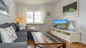 Een woonkamer met een bank, een salontafel, een televisie en een boekenkast.