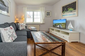 A living room with a sofa, a coffee table, a TV, and a bookshelf.
