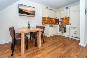 Une cuisine moderne avec des armoires blanches, un plan de travail en bois, un four encastré et un four à micro-ondes.