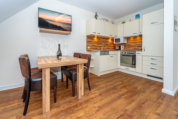 Eine moderne Küche mit weißen Schränken, einer Holz Arbeitsplatte, einem eingebauten Backofen und einer Mikrowelle.