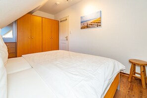 Quarto com cama, guarda-roupa de madeira e um quadro na parede.