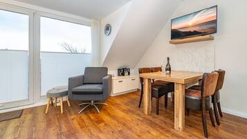 Ein modernes Schlafzimmer im Loft-Stil mit einem großen Dachfenster, einem Holzespeisetisch und einer gemütlichen Sitzecke.