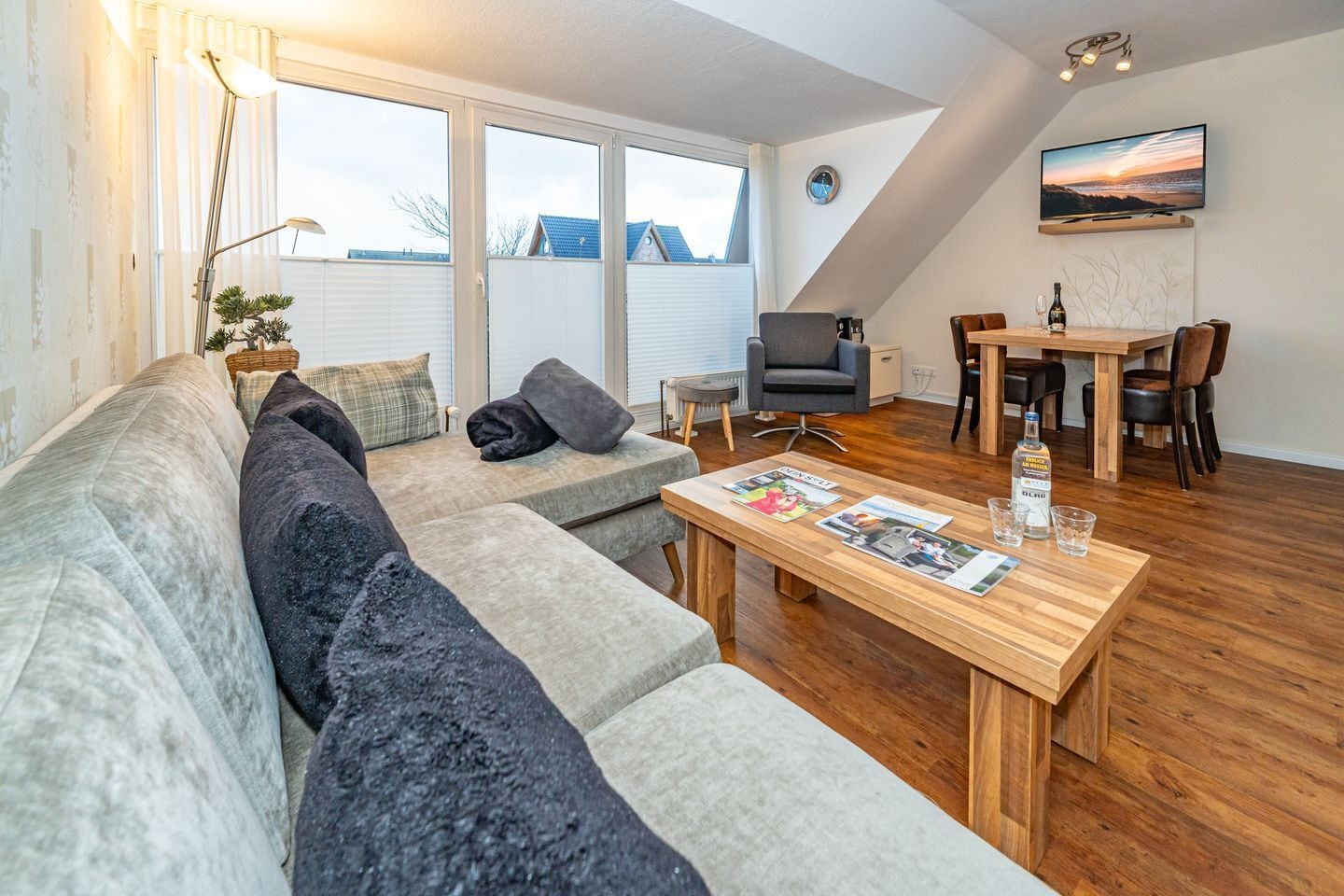 Una sala de estar moderna con un sofá, una mesa de comedor y un televisor montado en la pared.