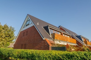 Une maison moderne avec un toit en pente, de grandes fenêtres et une façade en briques.