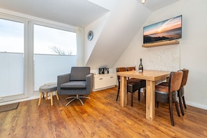 Une chambre de style loft moderne, dotée d’une grande lucarne, d’une table à manger en bois et d’un coin salon confortable.