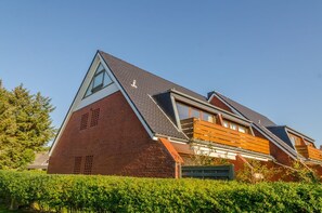 Uma casa moderna com telhado inclinado, janelas amplas e fachada de tijolos.