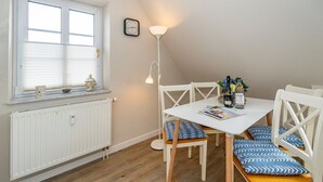 En matplats med ett vitt bord, blå- och vitmönstrade stolar, en golvlampa och ett fönster med persienner.