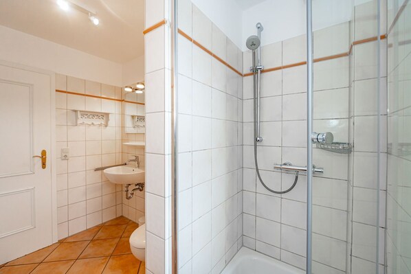 A modern bathroom with a glass-enclosed shower, a sink, and a toilet.