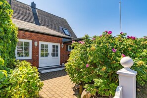 Een bakstenen huis met een betegelde entree en een witte deur.