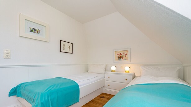 A bedroom with two single beds, a nightstand with two bedside lamps, and two framed pictures on the wall. - Wiip Hüs - Unter Reet Gebautes Hausteil in Keitum, mit Garten für bis zu 4 Personen (Sylt-Ost)