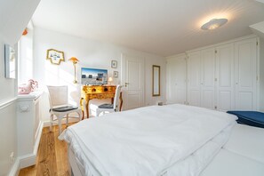 Une chambre à coucher avec un grand lit, un bureau avec une chaise, une commode et une armoire.