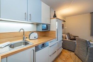 Een kleine keuken met een spoelbak, broodrooster, magnetron en een ingebouwde oven.
