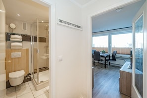 Une salle de bain moderne avec une douche à parois de verre, des toilettes et un porte-serviettes.